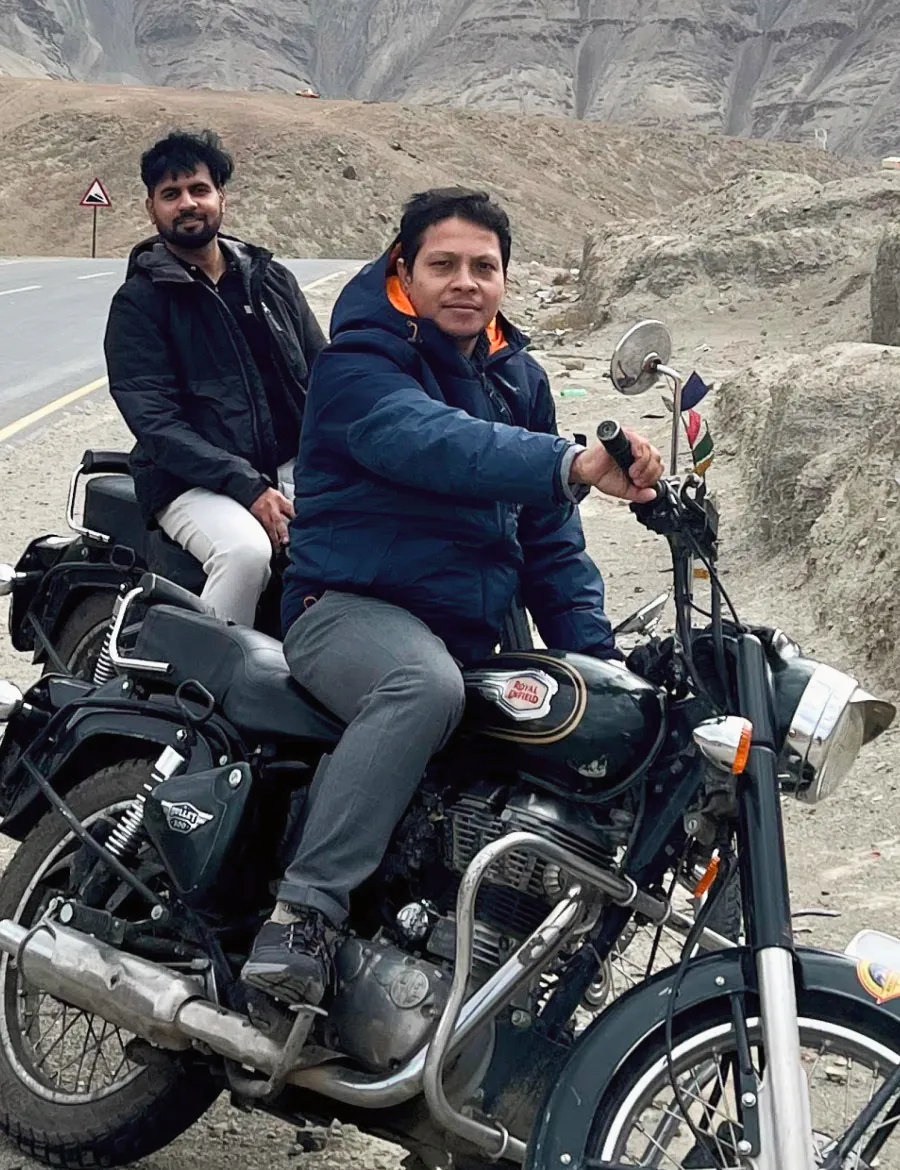On a Royal Enfield at the side of a high mountain road, a friend riding pillion.